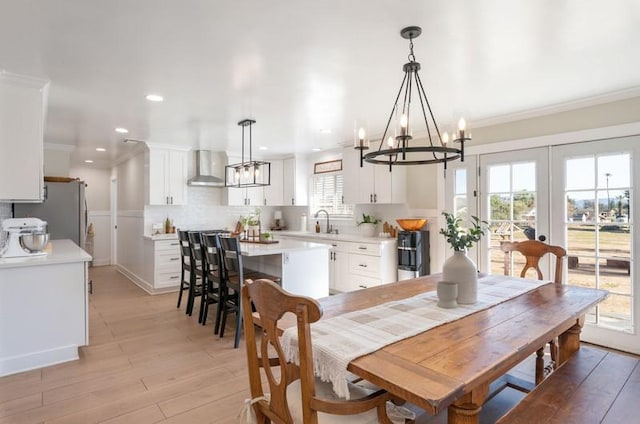 dining area featuring a chandelier, light wood-style flooring, recessed lighting, french doors, and ornamental molding