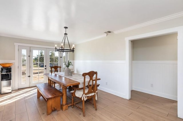 dining area featuring light wood-style floors, wainscoting, and visible vents