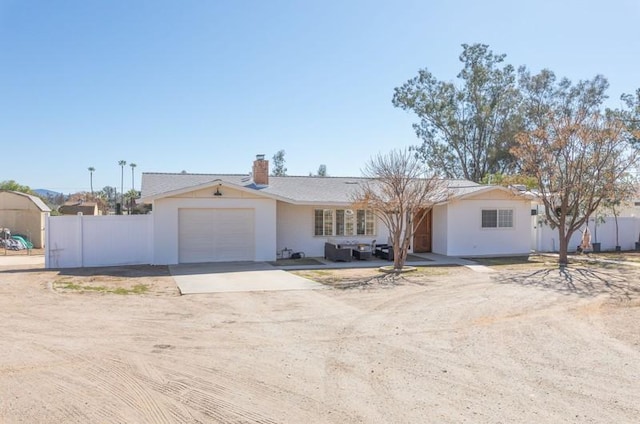 ranch-style home with dirt driveway, a chimney, an attached garage, and fence