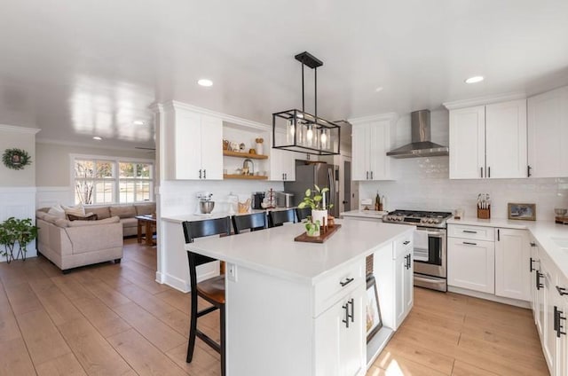 kitchen with stainless steel appliances, light countertops, light wood-type flooring, wall chimney exhaust hood, and a kitchen bar