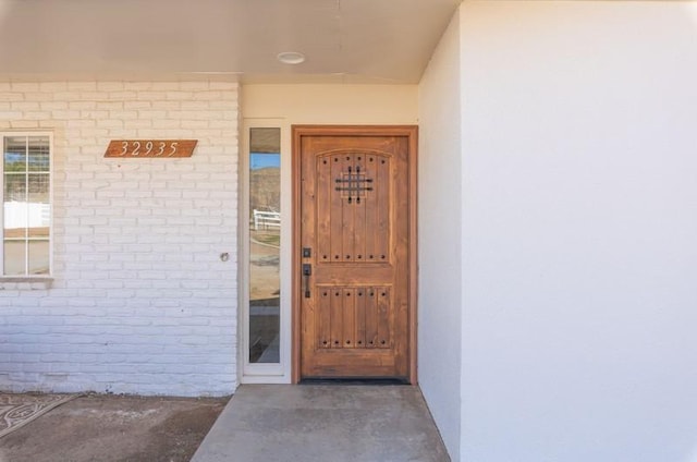 doorway to property with brick siding and stucco siding