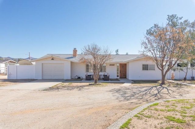 ranch-style house featuring driveway, a chimney, an attached garage, and fence