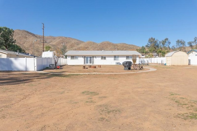 back of house featuring a storage shed, a fenced backyard, a mountain view, and an outdoor structure