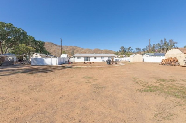 view of yard featuring an outbuilding, a shed, fence, and a mountain view