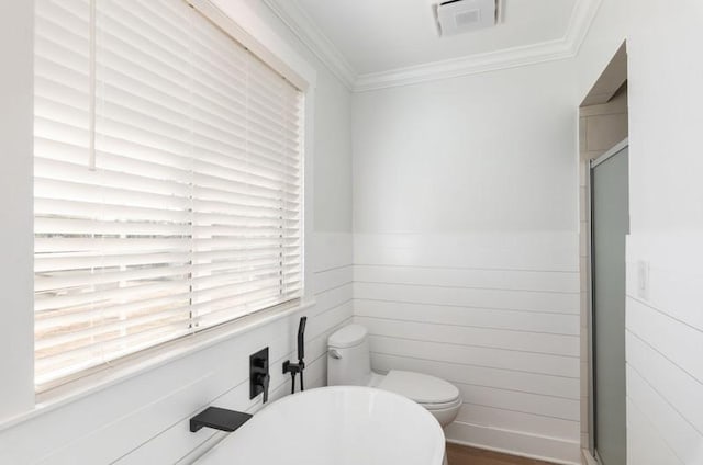 full bathroom featuring ornamental molding, a stall shower, a freestanding tub, and toilet