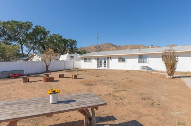 back of property featuring french doors, a fenced backyard, a mountain view, and central AC unit