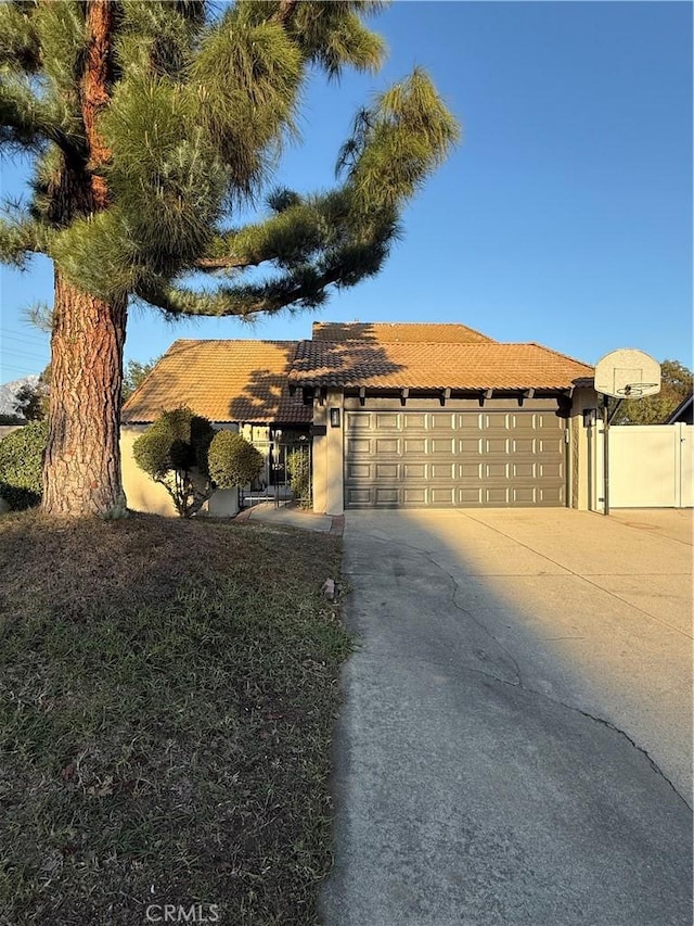 single story home with a garage, driveway, a tile roof, and stucco siding