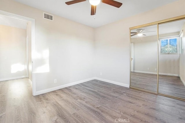 unfurnished bedroom with light wood-style floors, baseboards, visible vents, and a closet