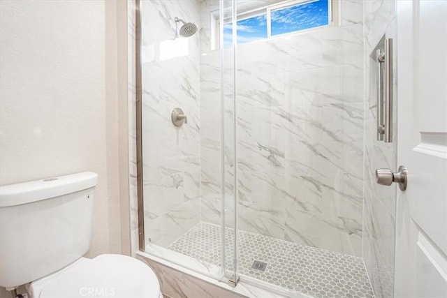 bathroom featuring toilet and a marble finish shower