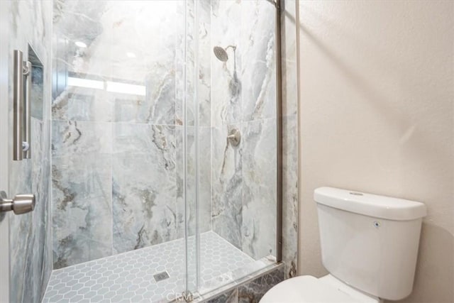 bathroom featuring a shower stall and toilet