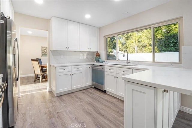 kitchen with light countertops, appliances with stainless steel finishes, a sink, and white cabinets