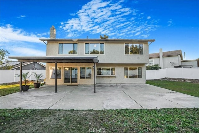 rear view of house with a patio, a chimney, a fenced backyard, and stucco siding