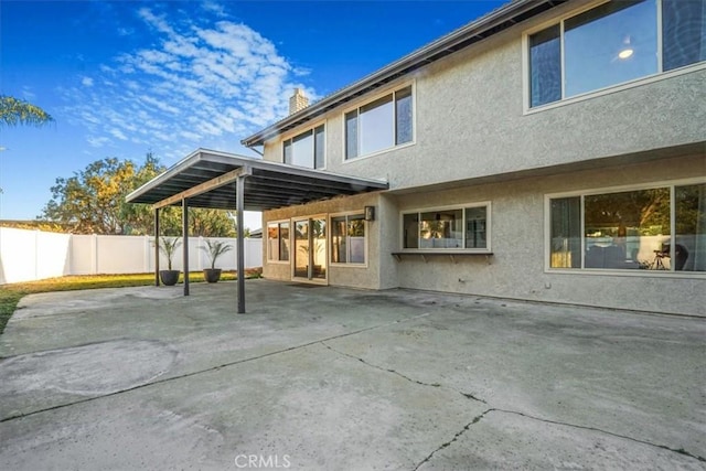 back of property with a fenced backyard, a patio, a chimney, and stucco siding