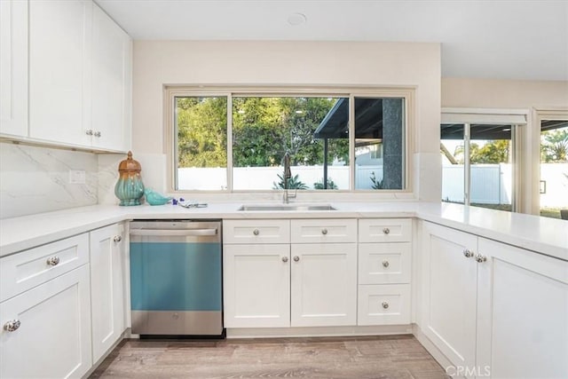 kitchen with light countertops, a sink, stainless steel dishwasher, and white cabinetry