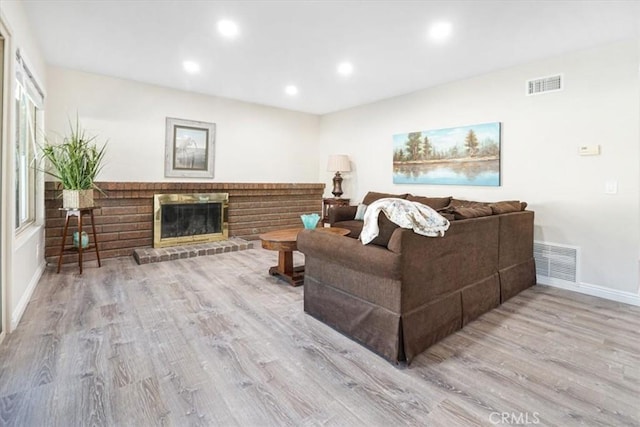 living room with recessed lighting, visible vents, a fireplace, and light wood finished floors