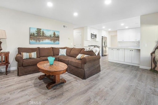 living area featuring recessed lighting, baseboards, visible vents, and light wood finished floors