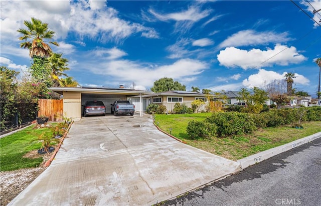 ranch-style home with a front yard, fence, a carport, and concrete driveway