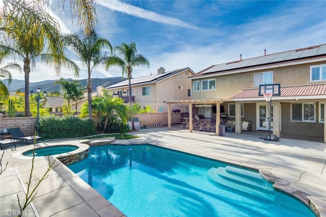 view of pool featuring a fenced backyard, an outdoor bar, a patio area, a pool with connected hot tub, and a mountain view