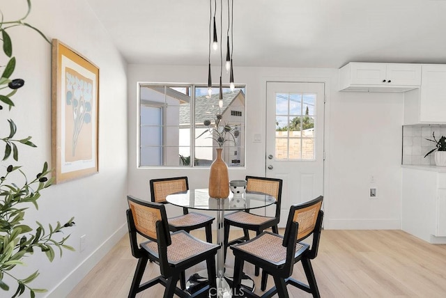 dining space with light wood-type flooring and baseboards