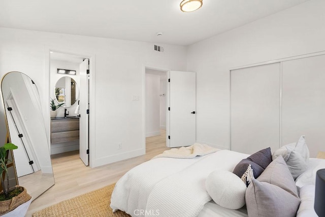 bedroom with baseboards, light wood-style flooring, visible vents, and a closet