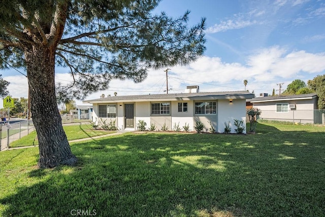 view of front facade featuring fence, a front lawn, and stucco siding