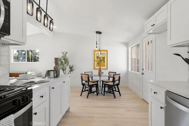 kitchen featuring pendant lighting, white cabinets, light countertops, and dishwasher