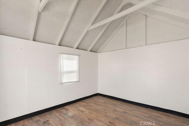 unfurnished room featuring dark wood-type flooring, vaulted ceiling with beams, and baseboards