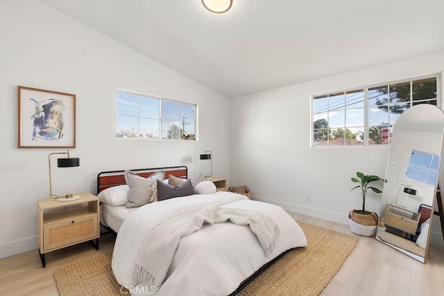 bedroom featuring light wood-style floors, baseboards, and vaulted ceiling