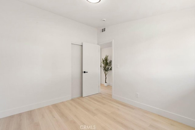 unfurnished room with baseboards, visible vents, and light wood-style floors