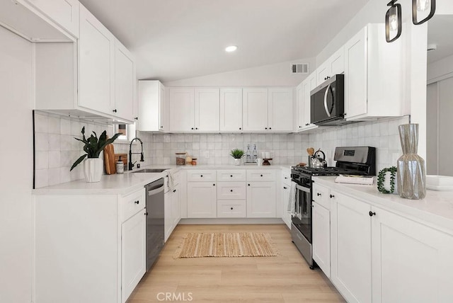 kitchen with appliances with stainless steel finishes, white cabinets, light countertops, and visible vents