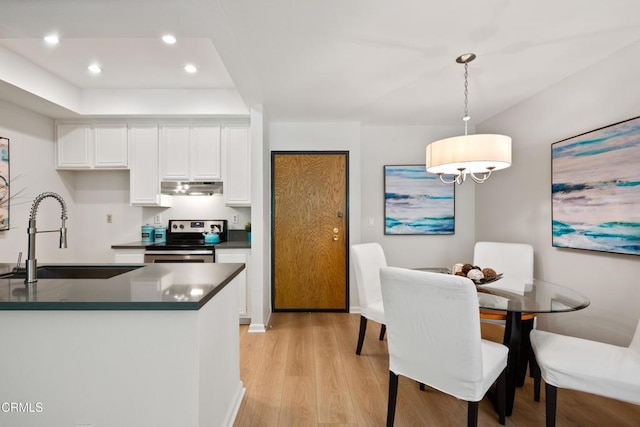 4200 Via Arbolada Unit 207, Los Angeles, CA 90042 - kitchen with electric stove, under cabinet range hood, light wood-style floors, dark countertops, and white cabinets