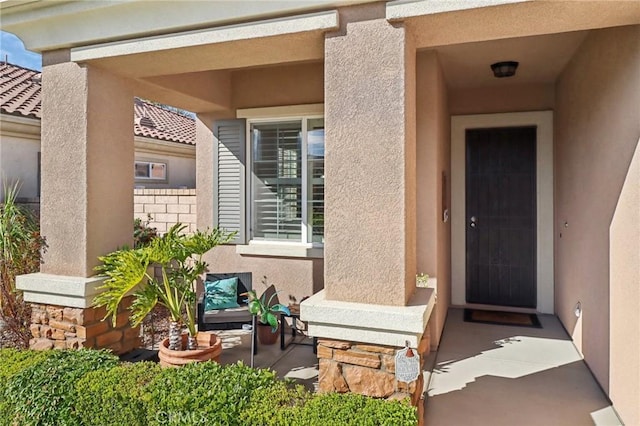 entrance to property featuring a tile roof and stucco siding