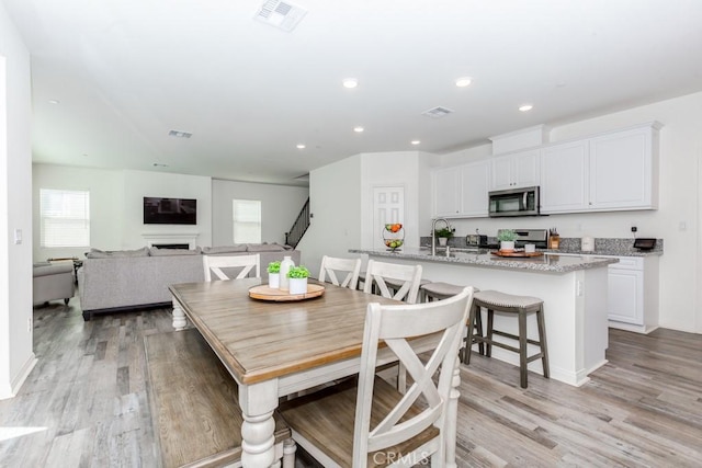 dining area with recessed lighting, visible vents, a fireplace, and light wood finished floors