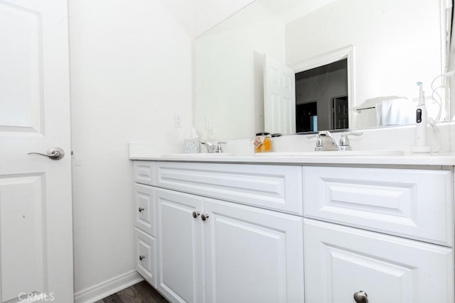 bathroom featuring a sink, baseboards, and double vanity