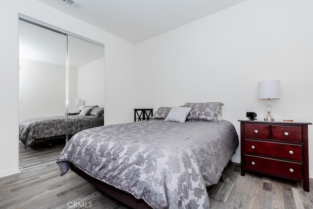 bedroom with a closet, visible vents, and wood finished floors