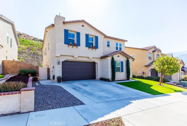 mediterranean / spanish home with a garage, fence, driveway, stucco siding, and a front yard