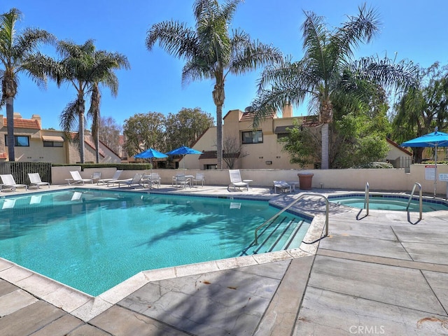 pool with a community hot tub, a patio, and fence