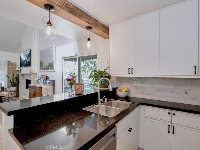 kitchen featuring decorative light fixtures, a fireplace, tasteful backsplash, white cabinetry, and a sink