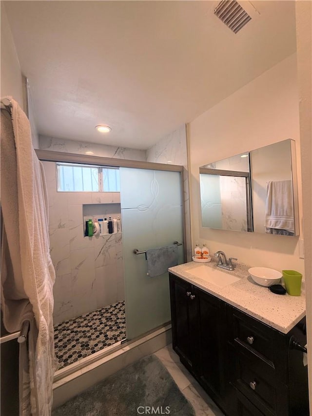 full bath featuring marble finish floor, visible vents, vanity, and a marble finish shower