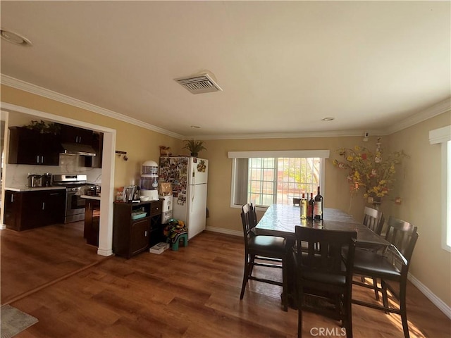 dining room with baseboards, dark wood-style flooring, visible vents, and crown molding