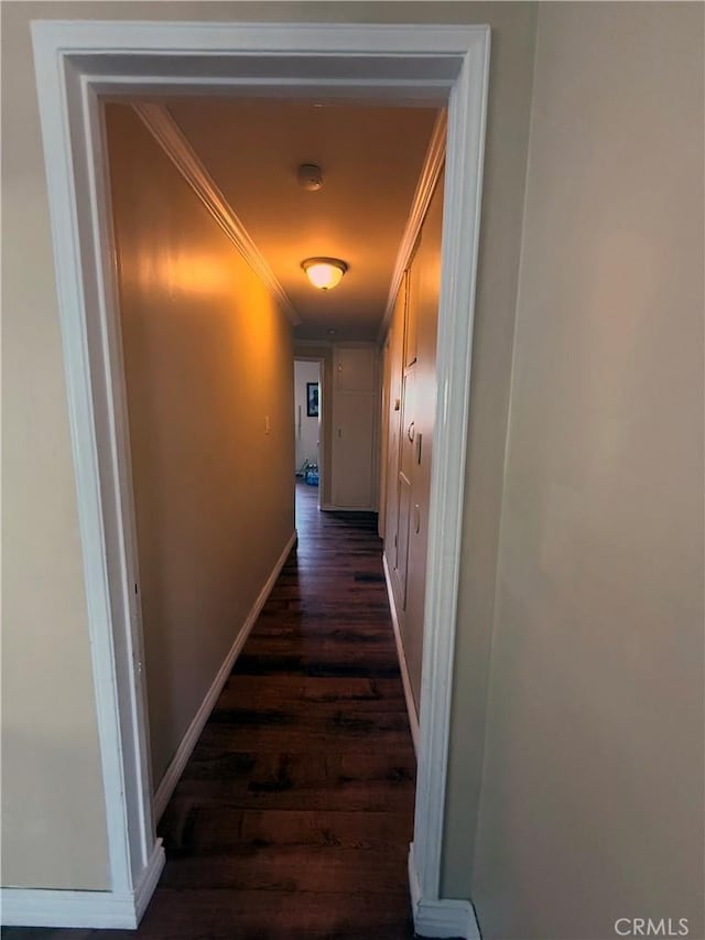 hallway with baseboards, ornamental molding, and dark wood finished floors