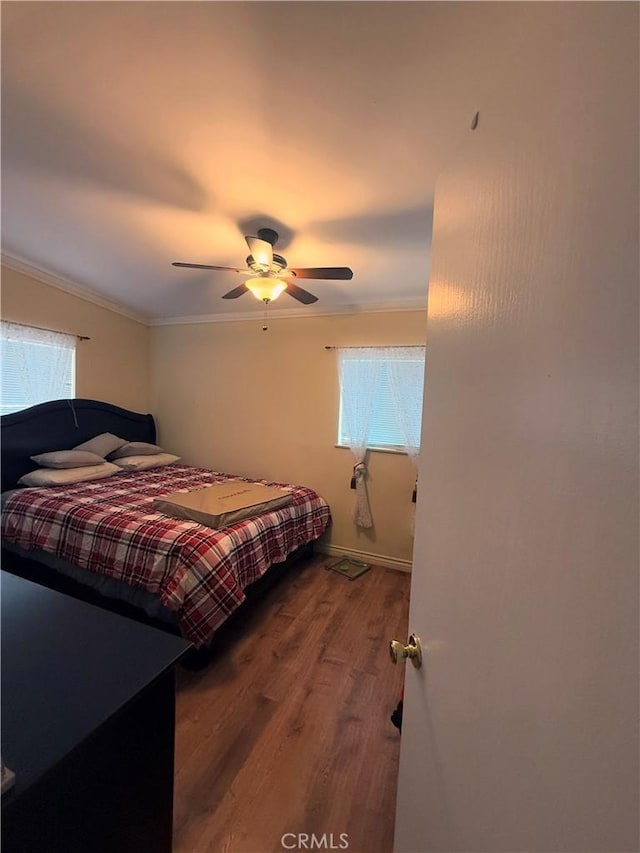 bedroom featuring baseboards, a ceiling fan, crown molding, and wood finished floors