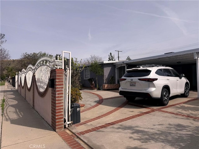 exterior space featuring driveway, fence, and a gate