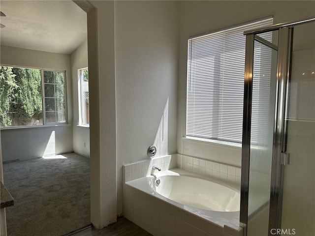 bathroom featuring a garden tub, a shower with door, and a textured wall