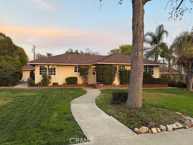 ranch-style home with stucco siding and a front yard