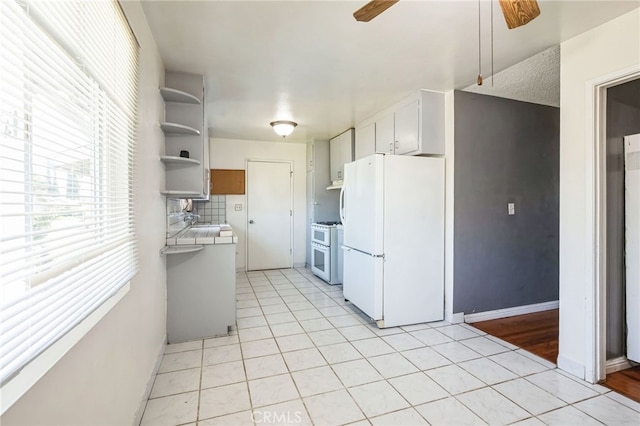 kitchen with tile countertops, white appliances, a ceiling fan, white cabinets, and backsplash