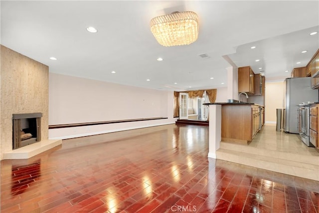 unfurnished living room featuring a large fireplace, a notable chandelier, dark wood finished floors, and recessed lighting