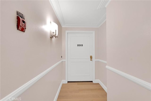 doorway to outside featuring light wood finished floors, baseboards, and crown molding