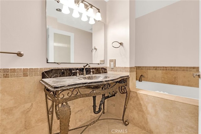 bathroom with a bathtub, tile patterned flooring, a sink, and tile walls