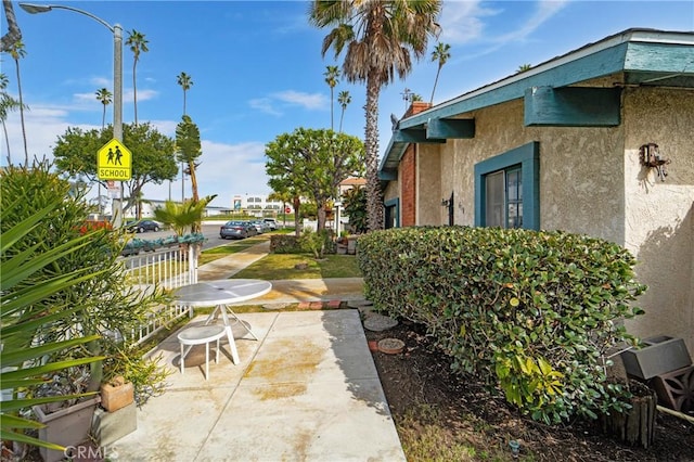 exterior space with a patio area, fence, and stucco siding